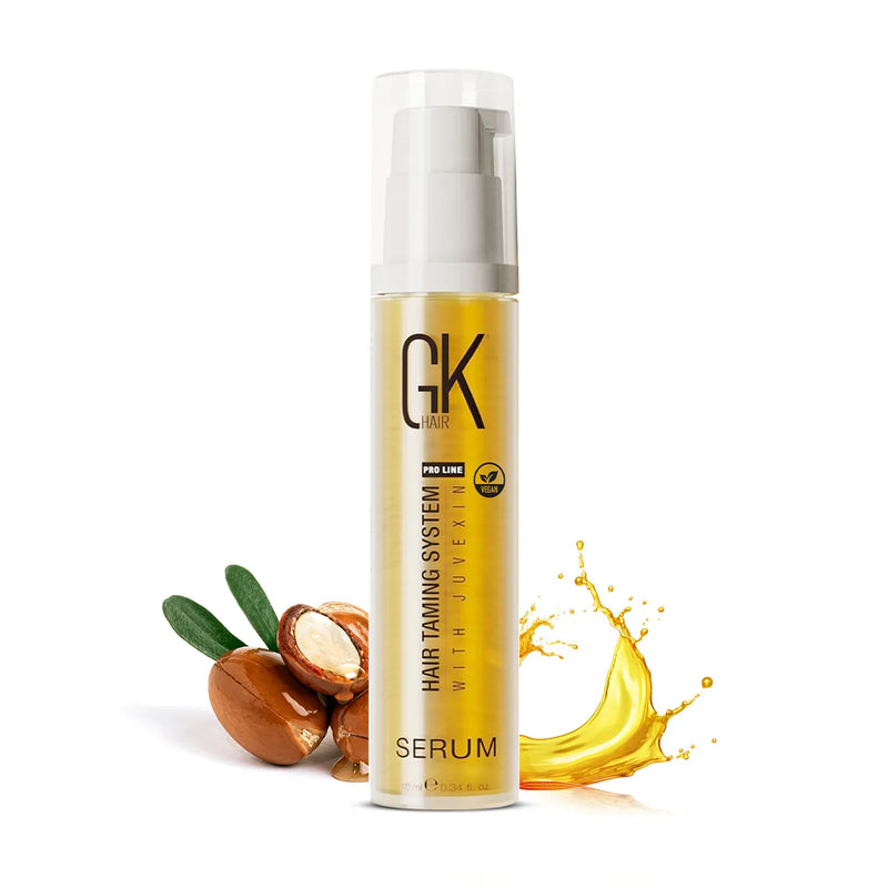 GK Hair Argan Oil Serum 10 ml gold pump bottle with white cap beside argan nuts and a splash of golden oil on white