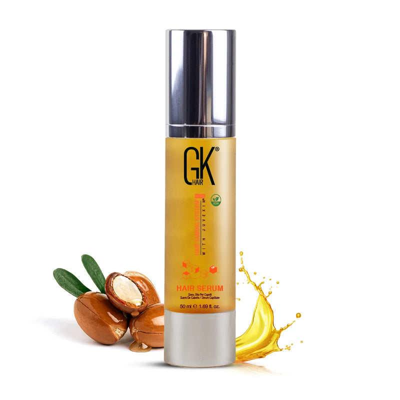 GK Hair Argan Oil Serum 50 ml gold pump bottle beside cracked argan nuts and a ribbon of golden oil on white