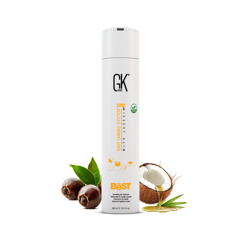 GK Hair The Best Smoothing Hair Treatment 300 ml white bottle beside jojoba nuts, green leaves and a coconut pouring oil