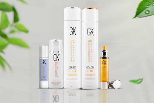 A collection of GK Hair products including moisturizing shampoo, conditioner, leave-in cream, and serum, arranged with green leaves.