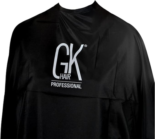 Close-up of a black GK Hair Professional salon cape with the white GK HAIR PROFESSIONAL logo across the chest