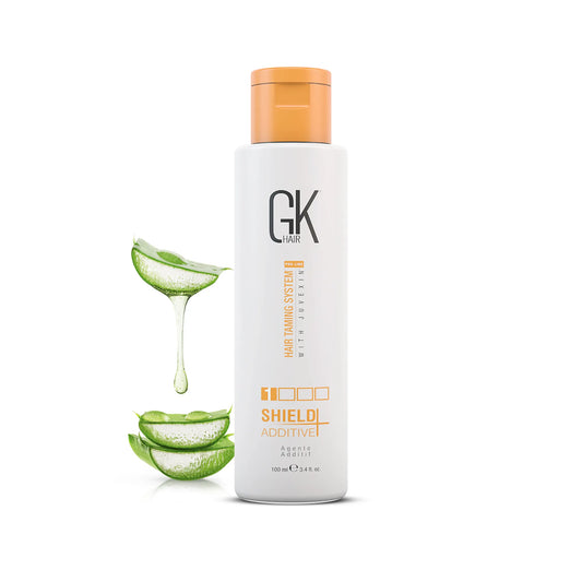 GK Hair Shield Additive+ 100 ml white bottle with orange cap beside aloe vera leaves dripping gel, on a white background