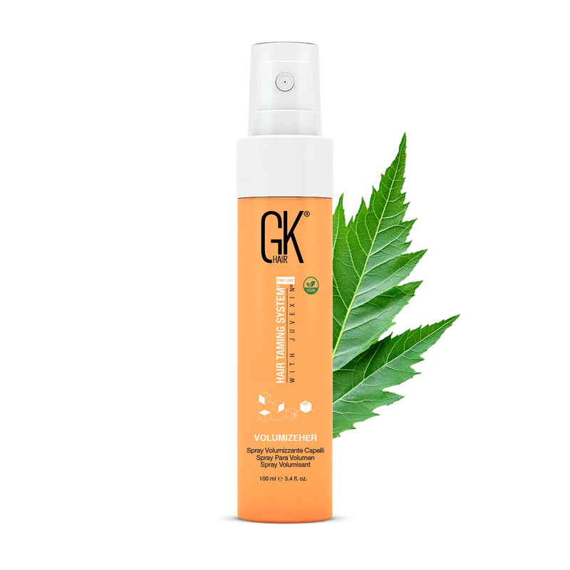 GK Hair VolumizeHer Volumizing Spray 100 ml orange bottle with white pump cap, a green leaf behind it, on a white background